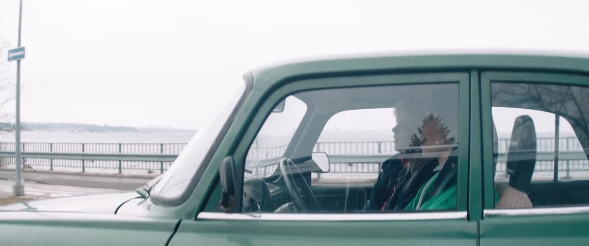Classic green vehicle in motion with two women inside