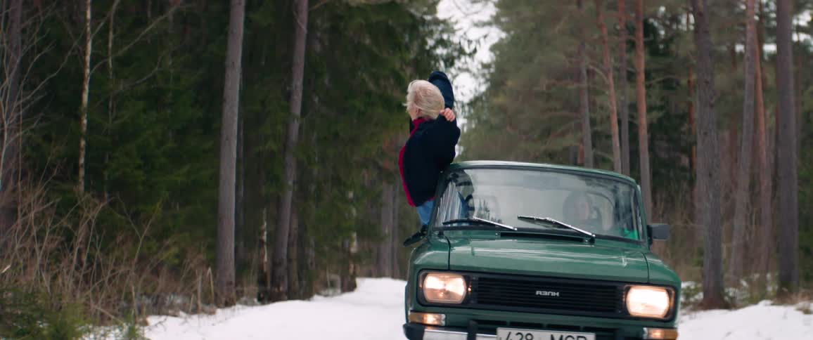 A woman hangs out of the moving vehicle