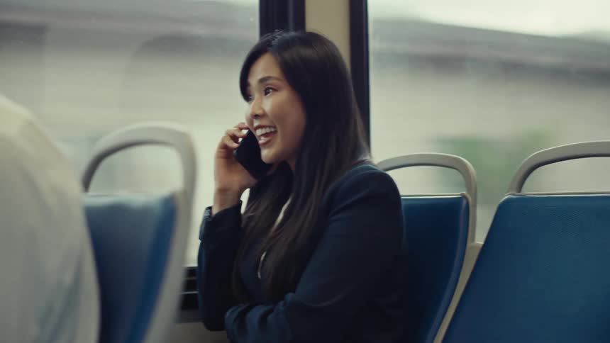 Womanriding on a bus laughs while talking on the phone