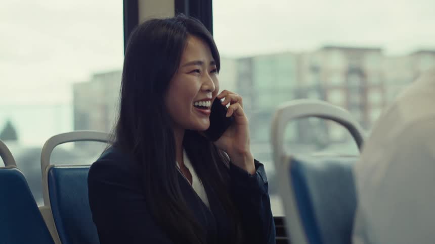 Woman sitting on the bussmiles while talking on her smartphone