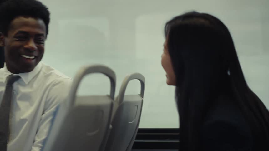 A man and a woman are laughing while riding in a train