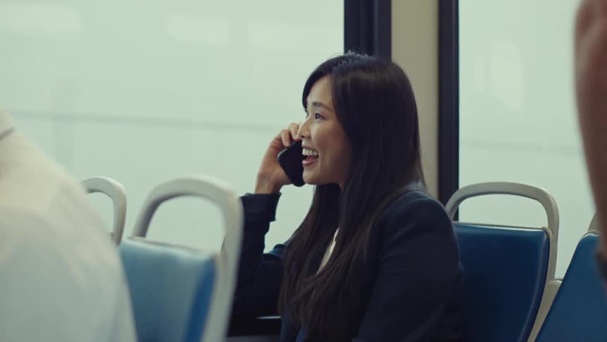 A woman smiles as she talks on her cellphone on a train