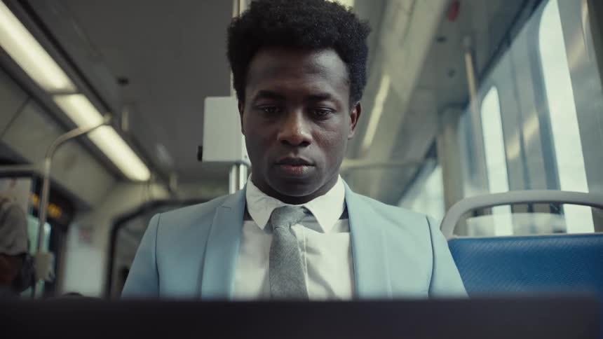 A man in a suit looks down as he rides the train