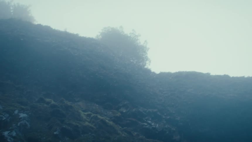 A smoky haze hangs over a rocky hill