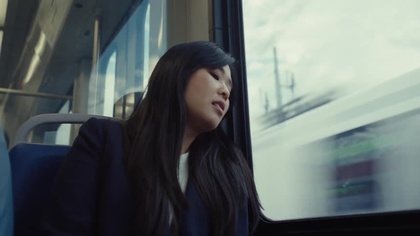 A woman is sad as she looks out a window on a train