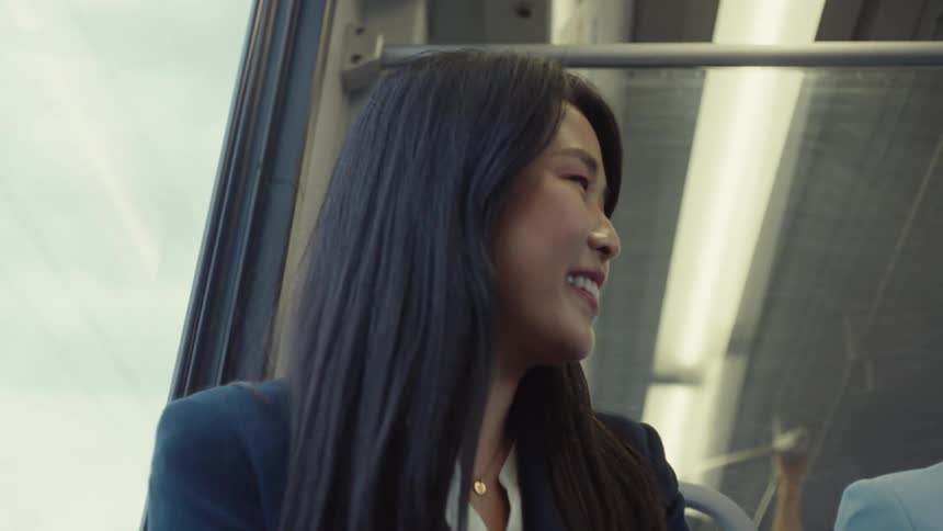 A woman with long dark hair is sitting by a train window engaged in a conversation
