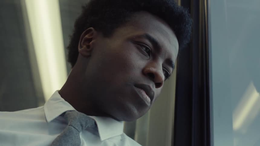 A man is deep in thought as he looks out the window of a train