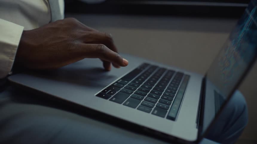 A man is typing on a laptop with one hand