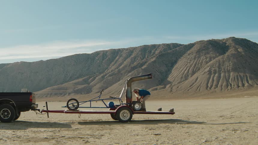 A man is unloading a jetpowered gokart from a trailer in a desert landscape