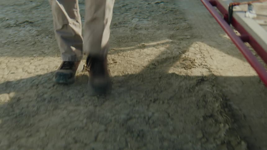 Man exits a vehicle parked in the desert and unfastens a buggy on a trailer