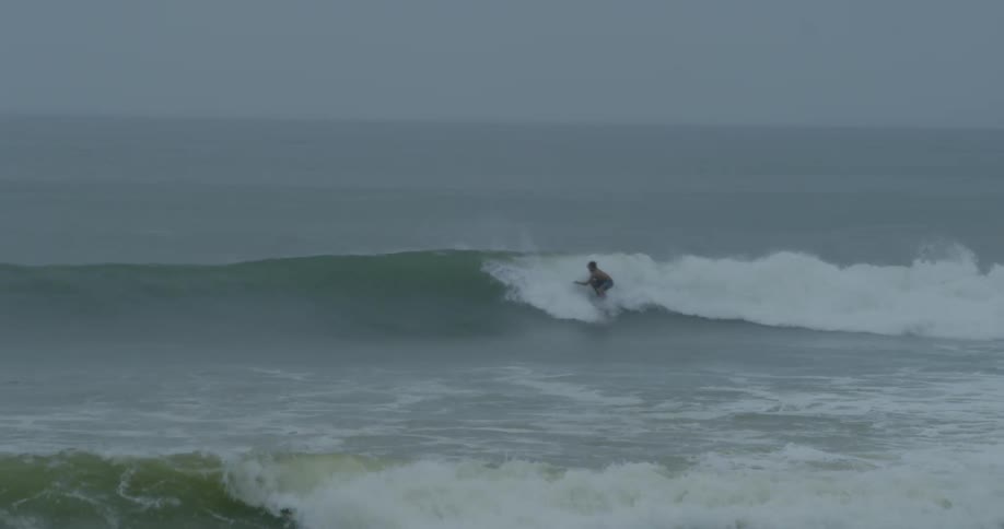 A surfer is riding a wave in the ocean while several other surfers wait in the background