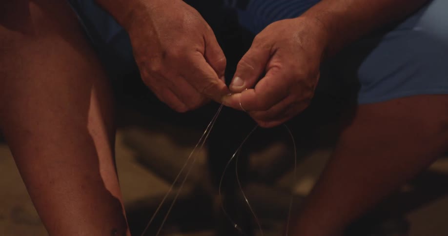 A mans hands carefully handling fishing line preparing fishing gear