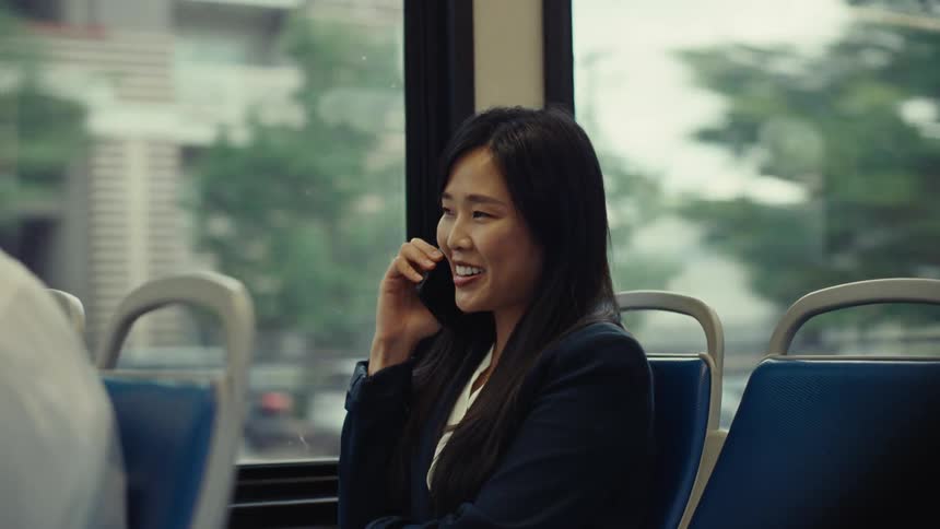 A woman laughs as she answers her phone on a train