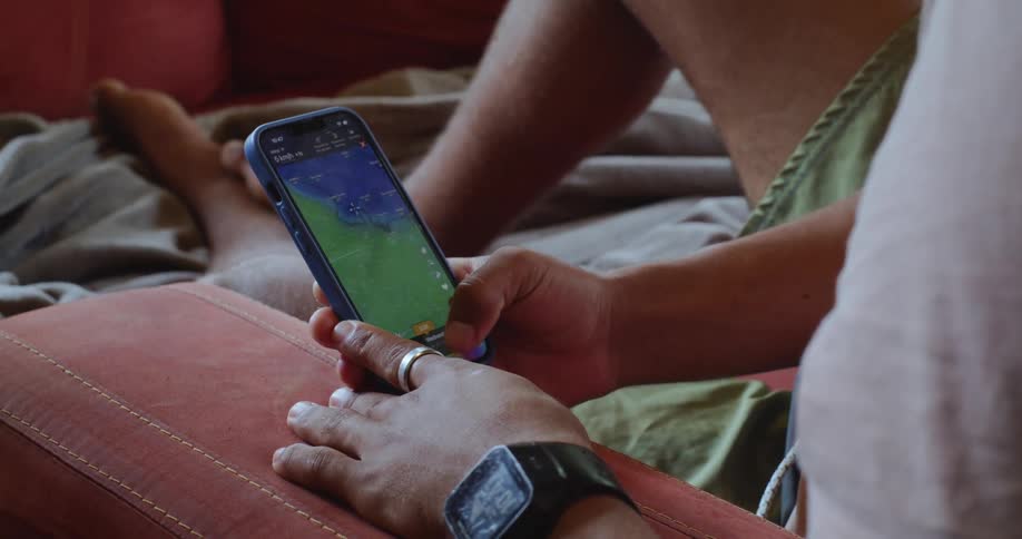A man is sitting down and scrolling on his phone