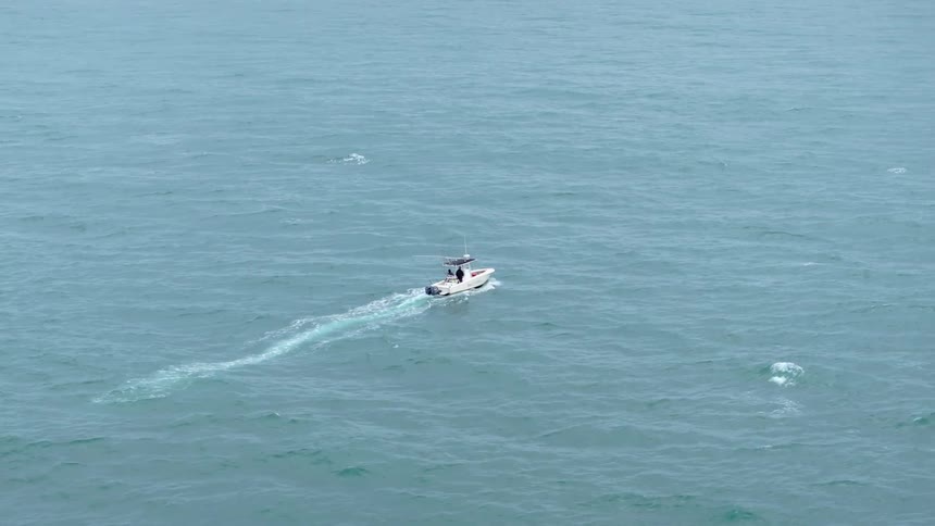 A boat travels across the ocean leaving a trail of white water behind it