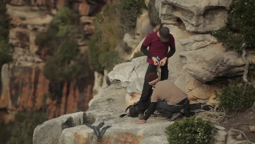 Two people setting something up on a cliff