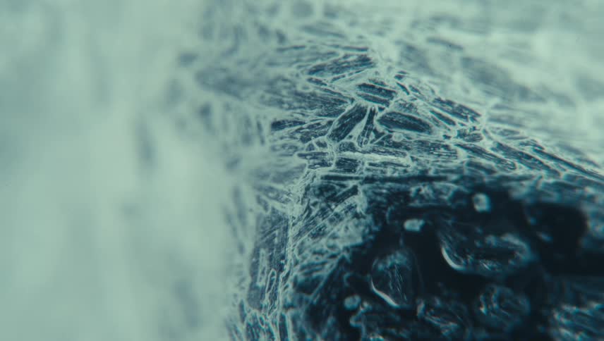Black fluid spreads on frosted surface after particles float around