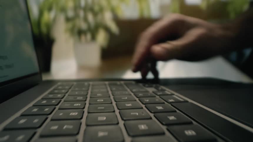 Man opens a laptop and touches a key on the keyboard