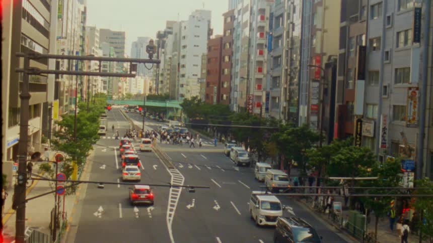 People cross on a sidewalk in a city with busy traffic