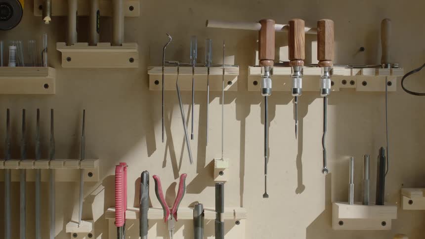 A well organized workshop with a variety of tools neatly displayed on a pegboard bathed in warm sunlight streaming through a window