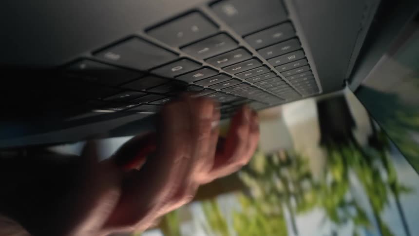 Closeup of a hand typing on a black laptop keyboard