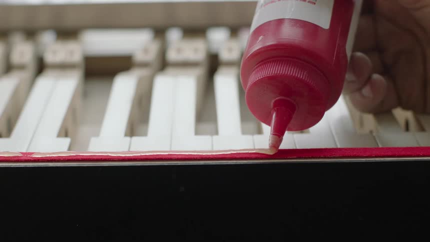 A person carefully uses a bottle of glue to lay down a straight line of glue