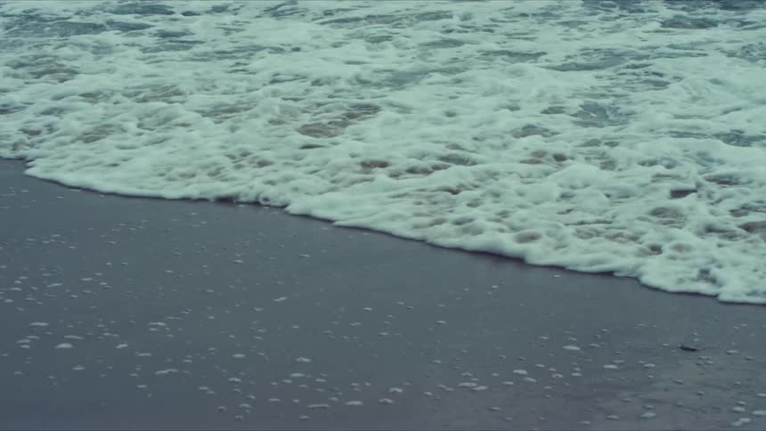 Water turns to foam as the wave hits the beach