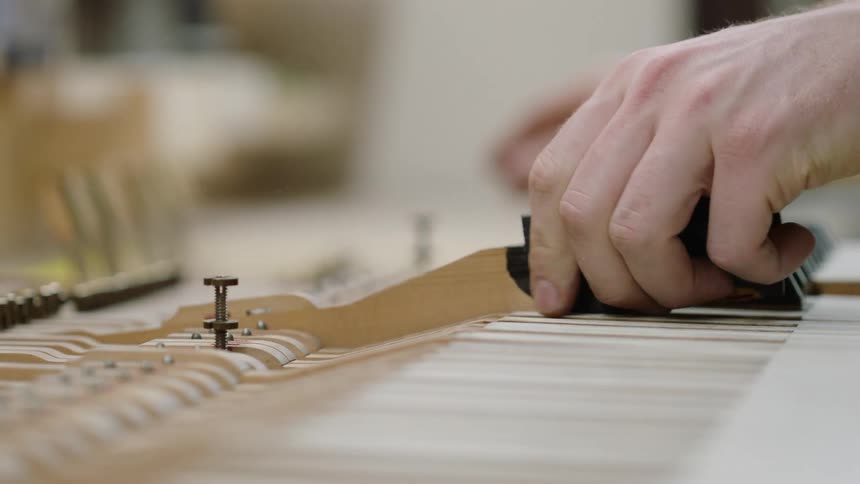 A person is removing piano keys as they work on assembly
