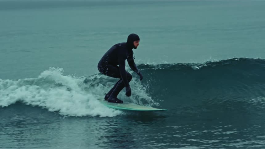 A man in a diving suit surfs the waves in the ocean