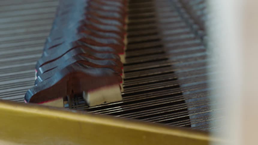 Closeup of a hand adjusting the hammer of a piano