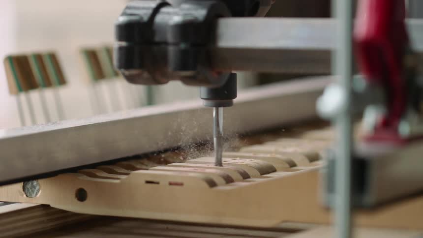A cnc machine precisely carves a wooden component creating a shower of sawdust