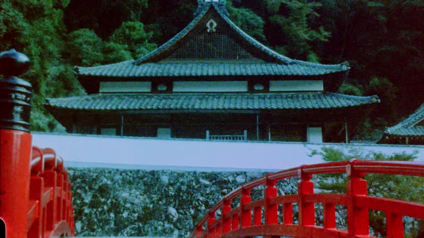 Temple with asian architecture and a red bridge in the foreground