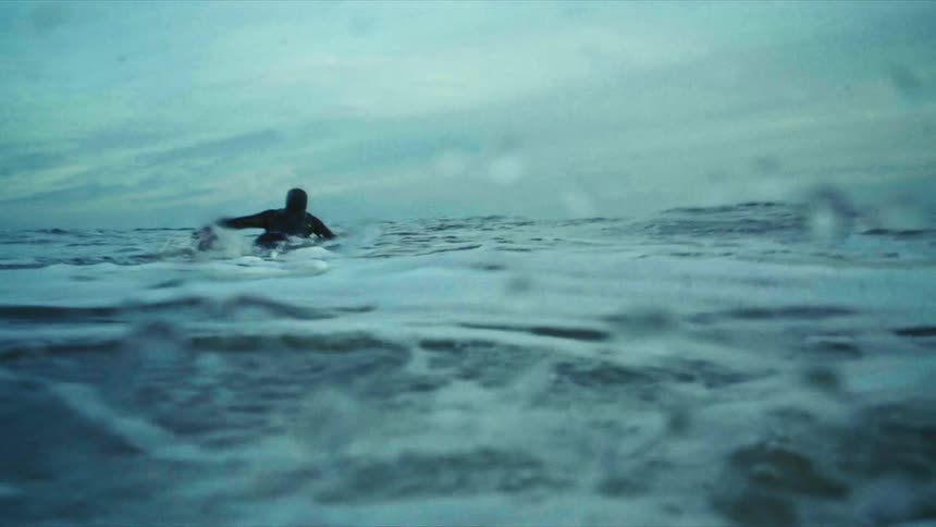Person swimming in the sea with surfboard