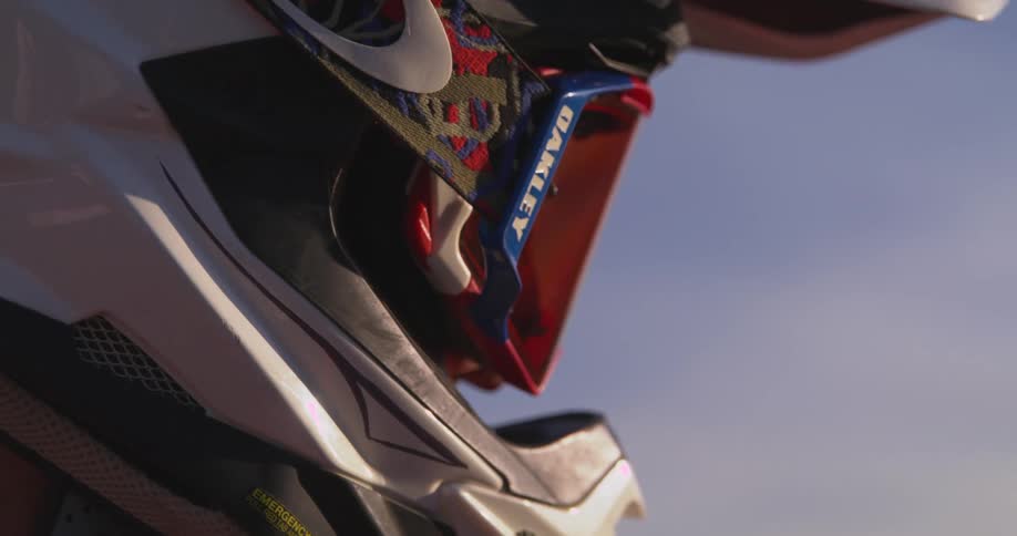 Closeup of a person wearing a motocross helmet with reflective red goggles