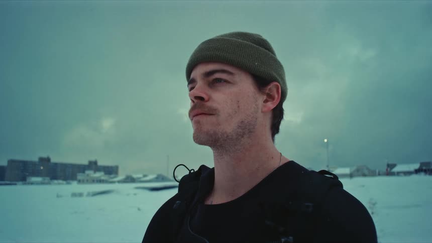 A man is standing outside looking around at the snow