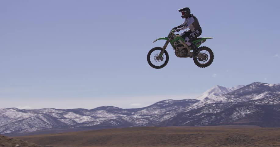 A man jumps his bike in the air as he moves on a dirt track