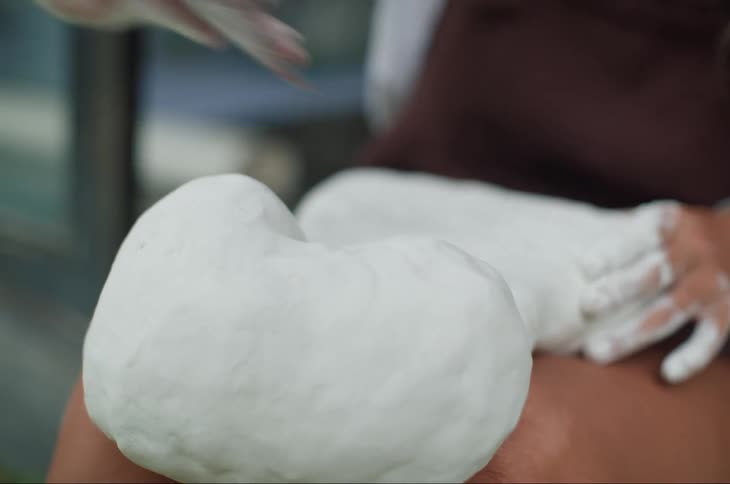 A woman is using a cloth to smooth out a sculpture