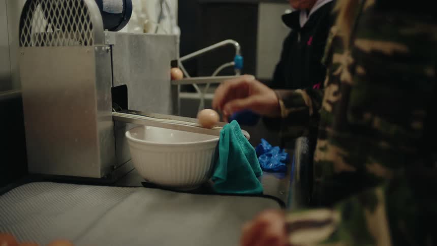 Two women taking eggs from a machine in the kitchen
