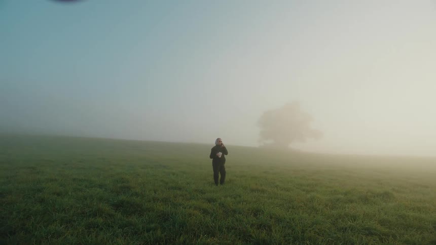 Woman talking on cell phone while standing in a foggy field