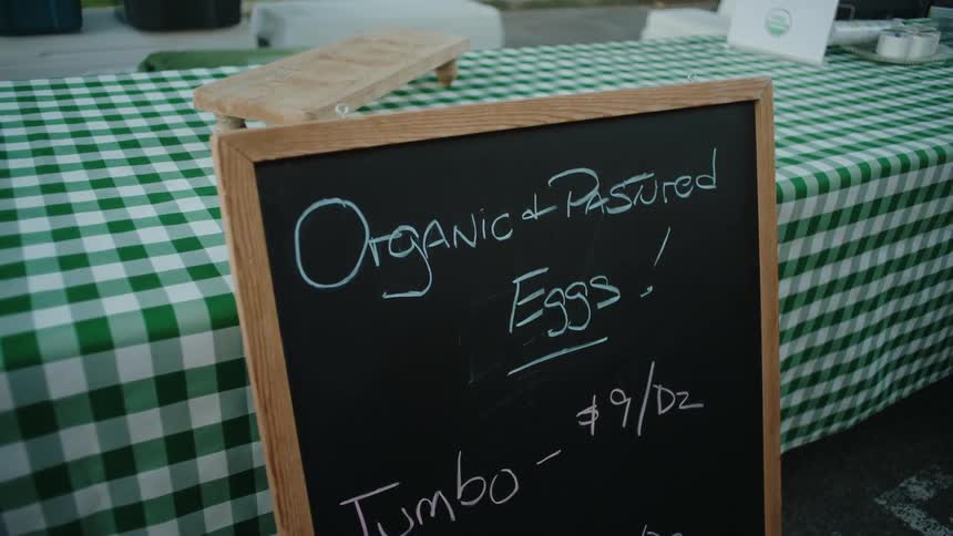 A chalkboard sign on a table with a green and white checkered tablecloth