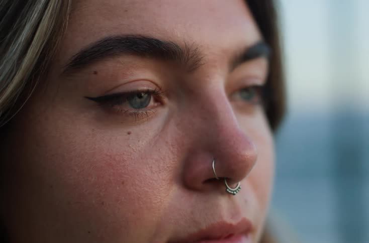 Closeup of a womans eyes and nose showcasing her clear eyes and multiple nose rings
