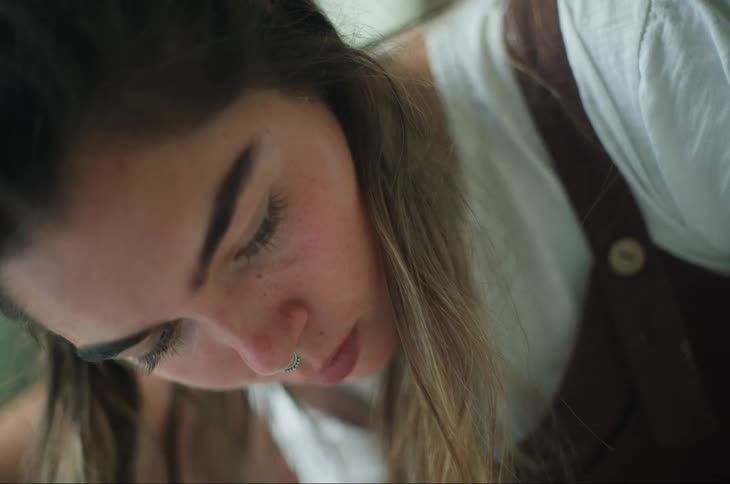 Concentrated blonde woman looking down while wearing a brown apron