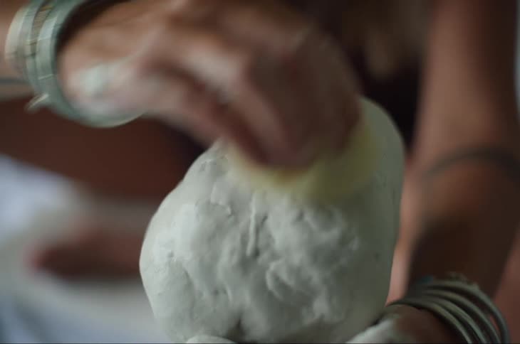 A woman polishes clay with a sponge