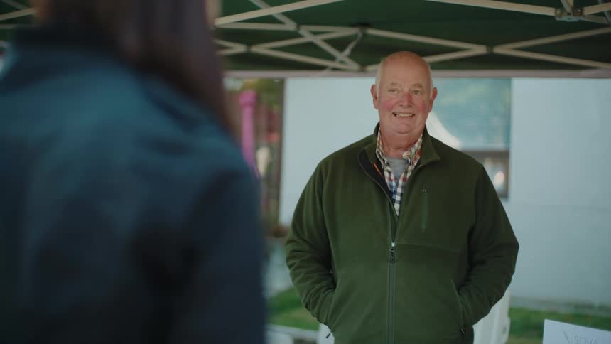 A man smiles and nods as he talks to a woman
