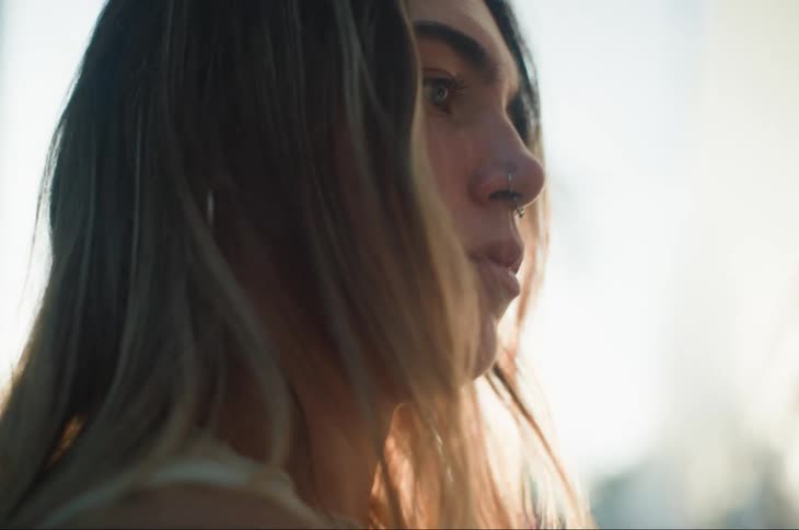 A woman is looking at something as the wind blows her hair