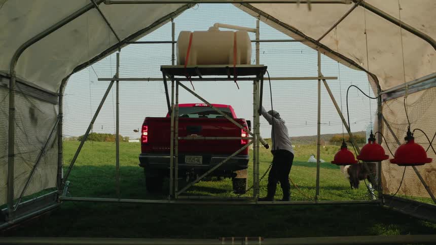 Red pickup truck parking in reverse next to a greenhouse
