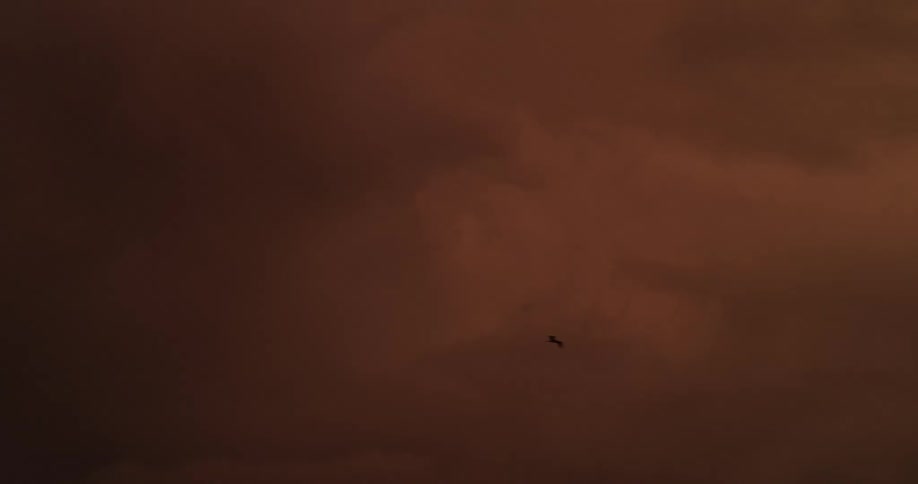 Red tinted clouds contrast with the surrounding darkness