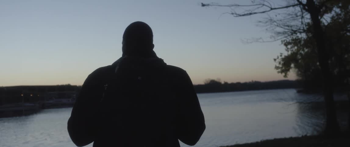 A person walks towards the water at dusk