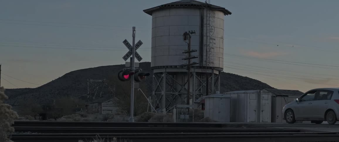 A car crosses railroad tracks while the train signal is flashing