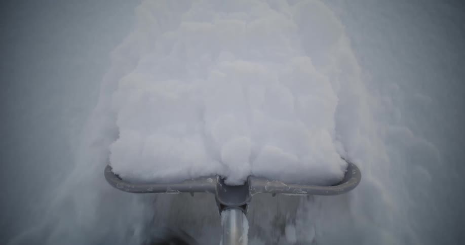 Someone is pushing a metal shovel through the snow in the morning